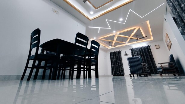 Zona pranzo moderna con ventilatore a soffitto, lampade geometriche e pavimento riflettente.