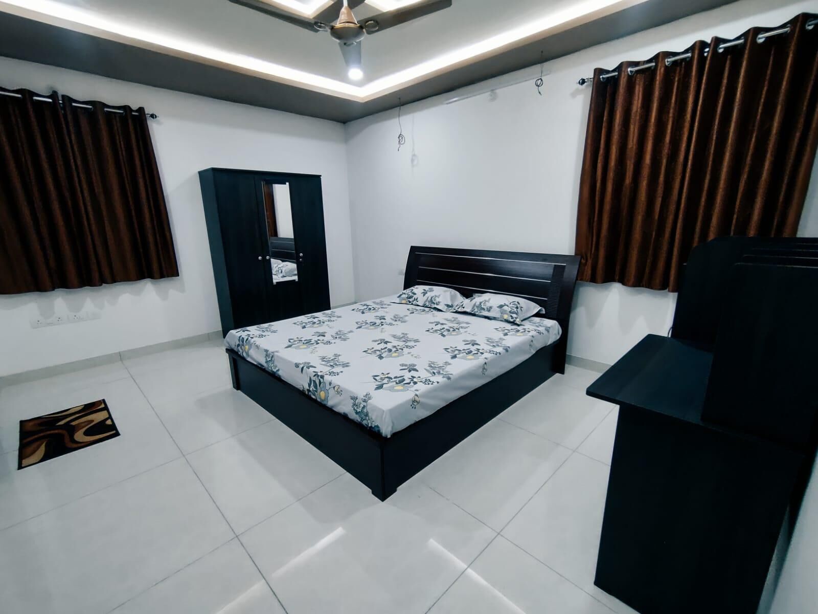 A bedroom with a bed, a wardrobe, a desk, and a ceiling fan.