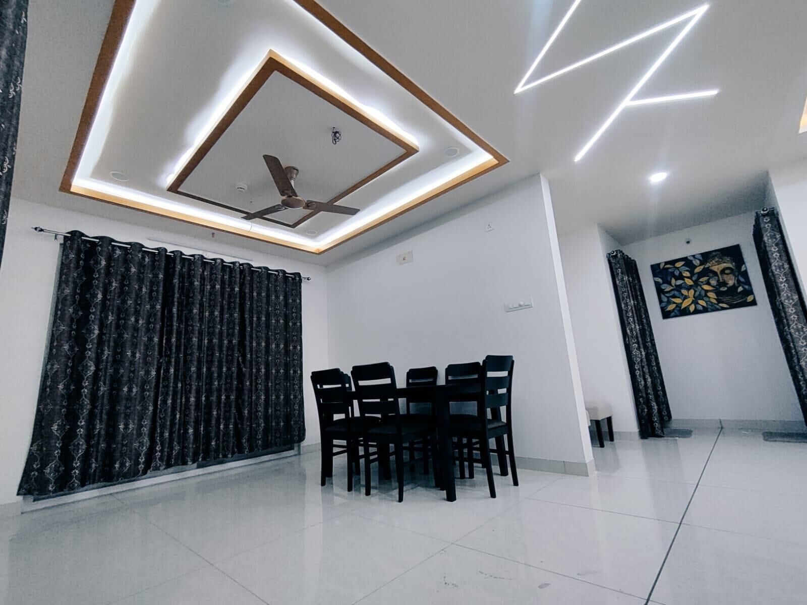 A modern dining area with a ceiling fan, recessed lighting, and a dining table with chairs.