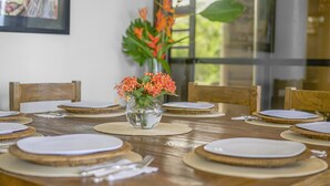 A dining table set with plates, cutlery, and a vase with flowers. - Villa La Loma, Oceanview, Private Pool and AC! (Tarcoles)