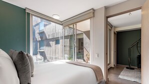 Quarto com uma cama grande, porta de vidro deslizante que dá para uma varanda e escada para outro cômodo.