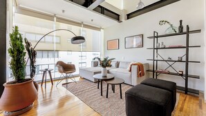 Uma sala de estar moderna com sofá, apoio para os pés, mesa de centro e plantas em vasos.