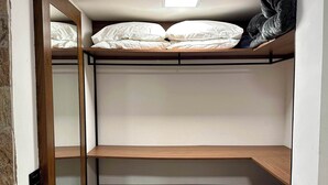 Habitación pequeña con literas, un estante y un espejo.