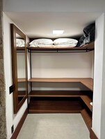 Habitación pequeña con literas, un estante y un espejo.