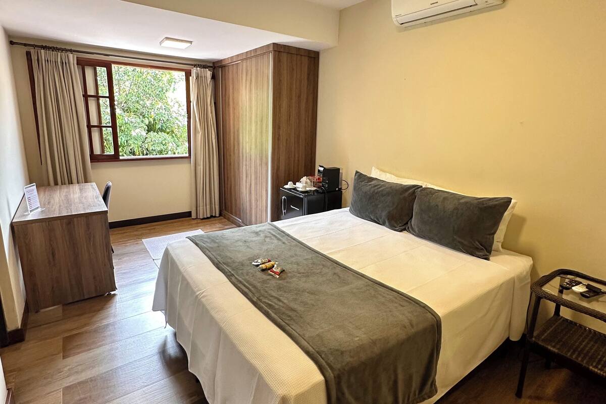 Una habitación de hotel moderna con una cama grande, un escritorio y una ventana con cortinas.