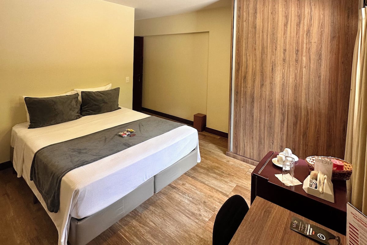 Una habitación de hotel con una cama, un escritorio y un armario de madera.