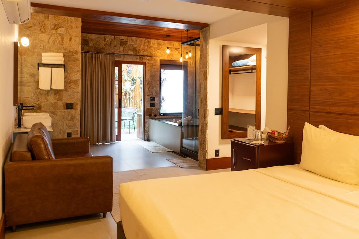 Habitación de hotel con cama, escritorio, silla, baño y vistas al exterior.