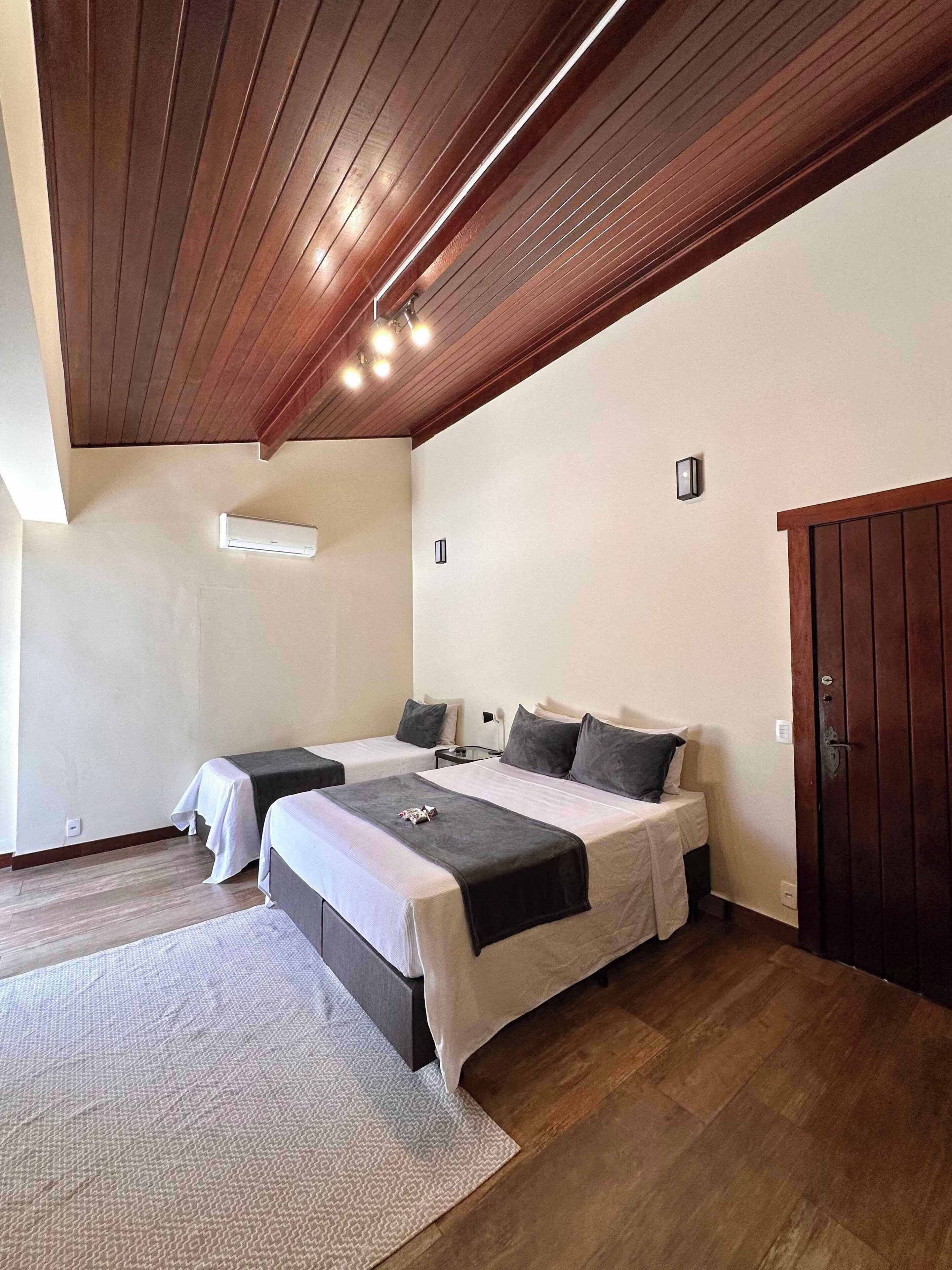 A bedroom with two beds, a ceiling fan, and a wooden door.