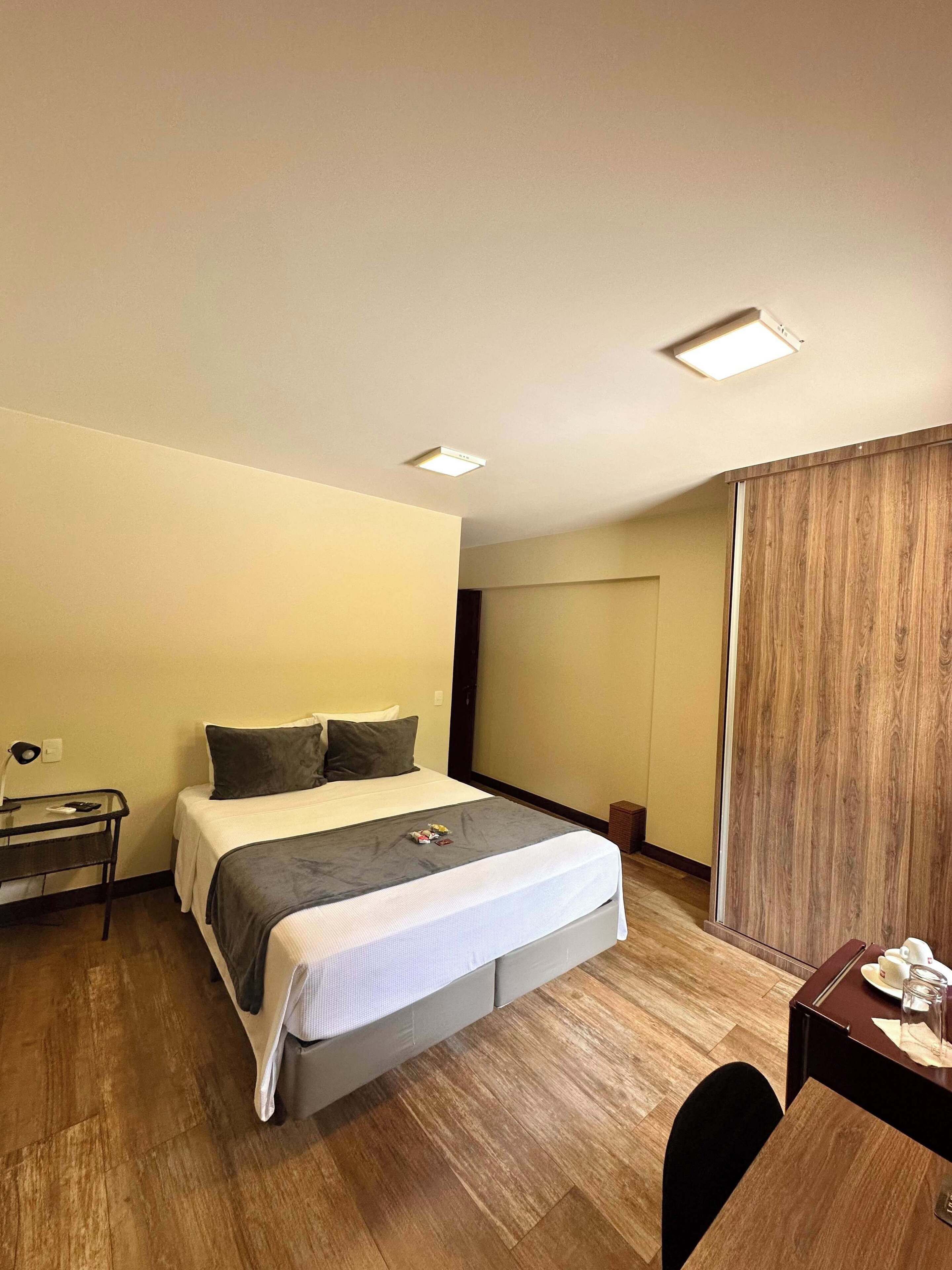 Una habitación de hotel con cama, mesita de noche y escritorio con silla.