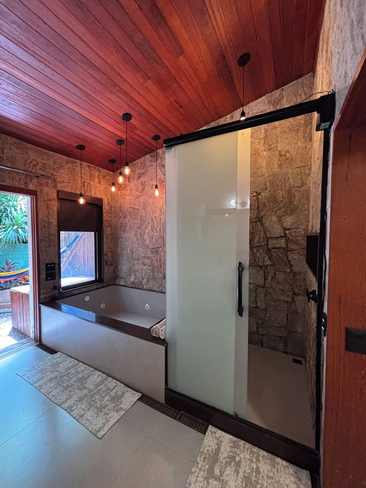 A modern bathroom with a glass shower enclosure, a bathtub, and a large mirror.