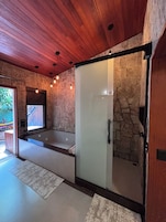 Casa de banho moderna com cabine de duche em vidro, banheira e um espelho grande.