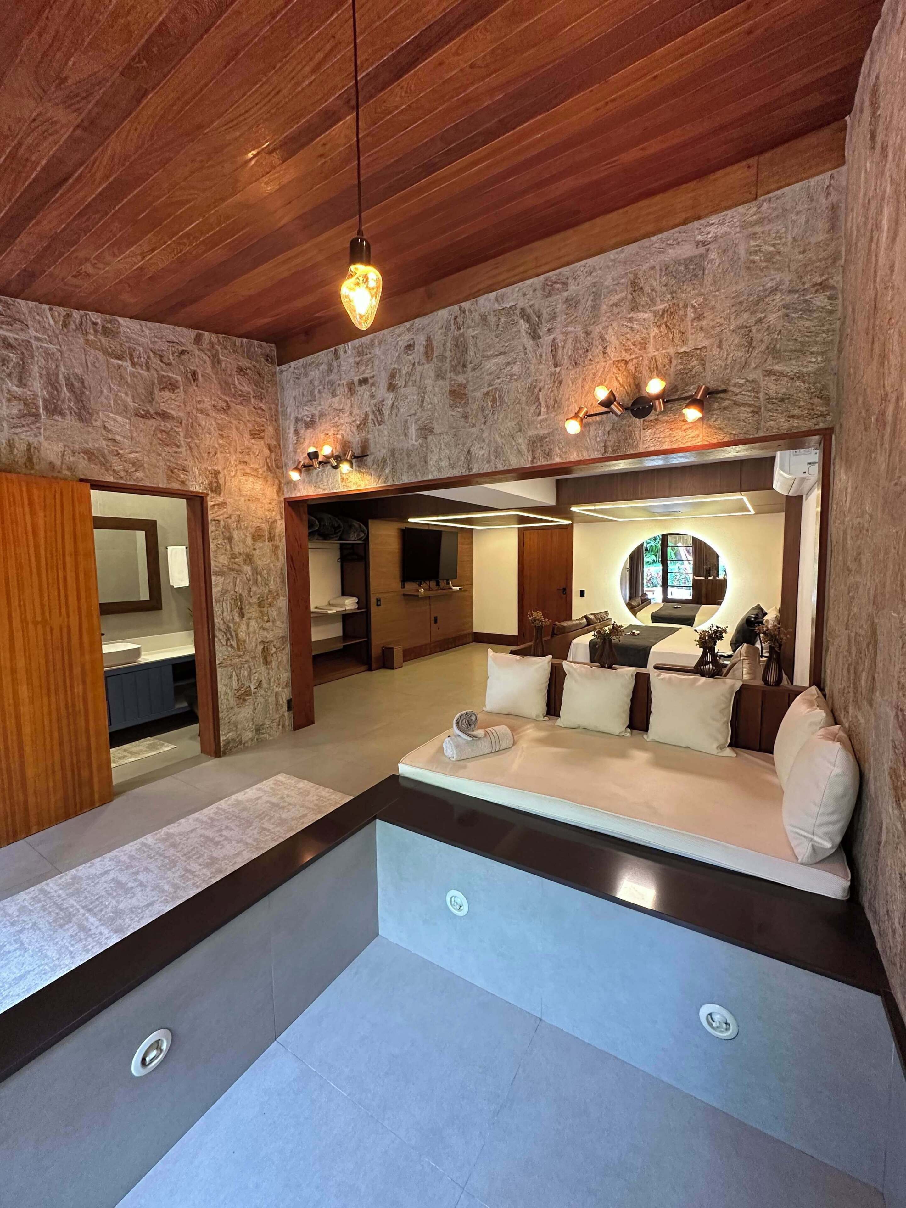 A modern interior with a stone wall, a wooden ceiling, and a seating area with cushions.