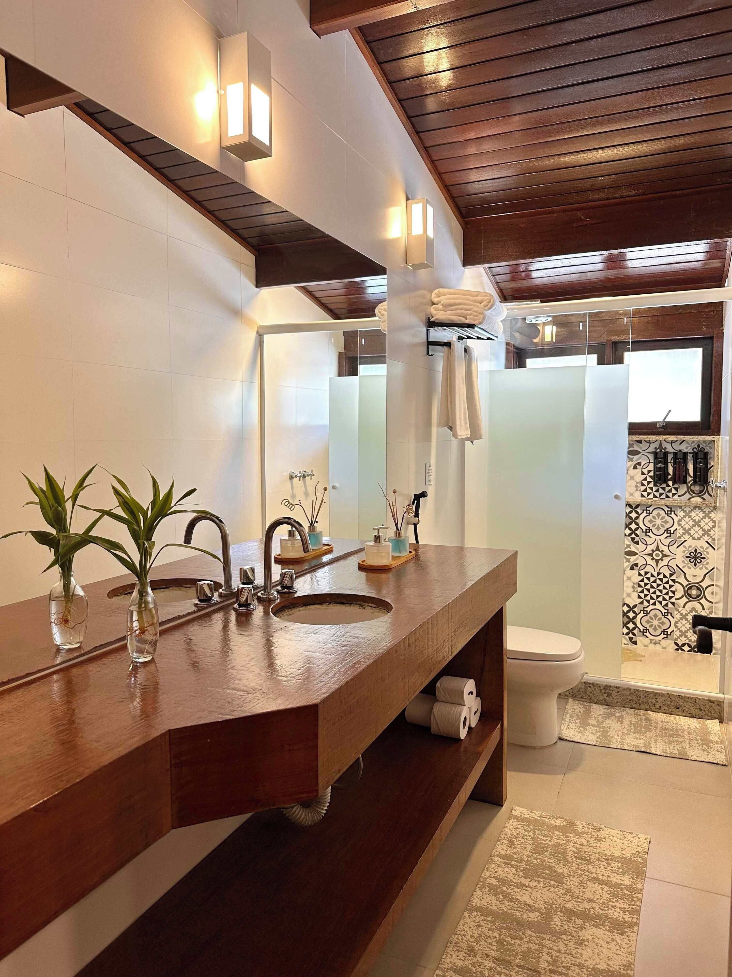 Un baño moderno con tocador de madera, un espejo grande y cabina de ducha.