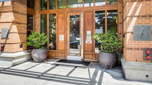 La entrada de un hotel con puertas dobles de madera, un acceso de vidrio y dos grandes macetas.