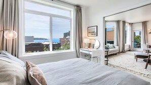 Habitación de hotel con un ventanal grande, una cama, un escritorio, un sofá y una silla.