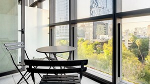 A balcony with a table and bench, large windows, and a city view. - Blueground Josefa by Urbanistas CDMX (Mexico City)