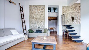 A living room with a wooden coffee table, a grey sofa, a stone wall, and a staircase with blue steps.