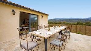 An outdoor dining area with a table set for four, surrounded by metal chairs with cushions.
