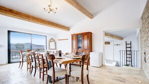 A spacious dining area with a large table, wooden chairs, and a view of the outdoors.