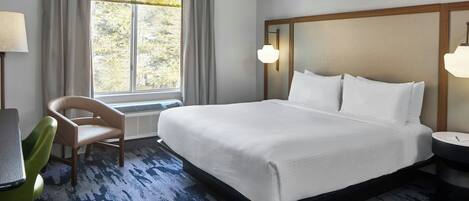 Una habitación de hotel con una cama grande, una silla, un escritorio y una ventana con cortinas.