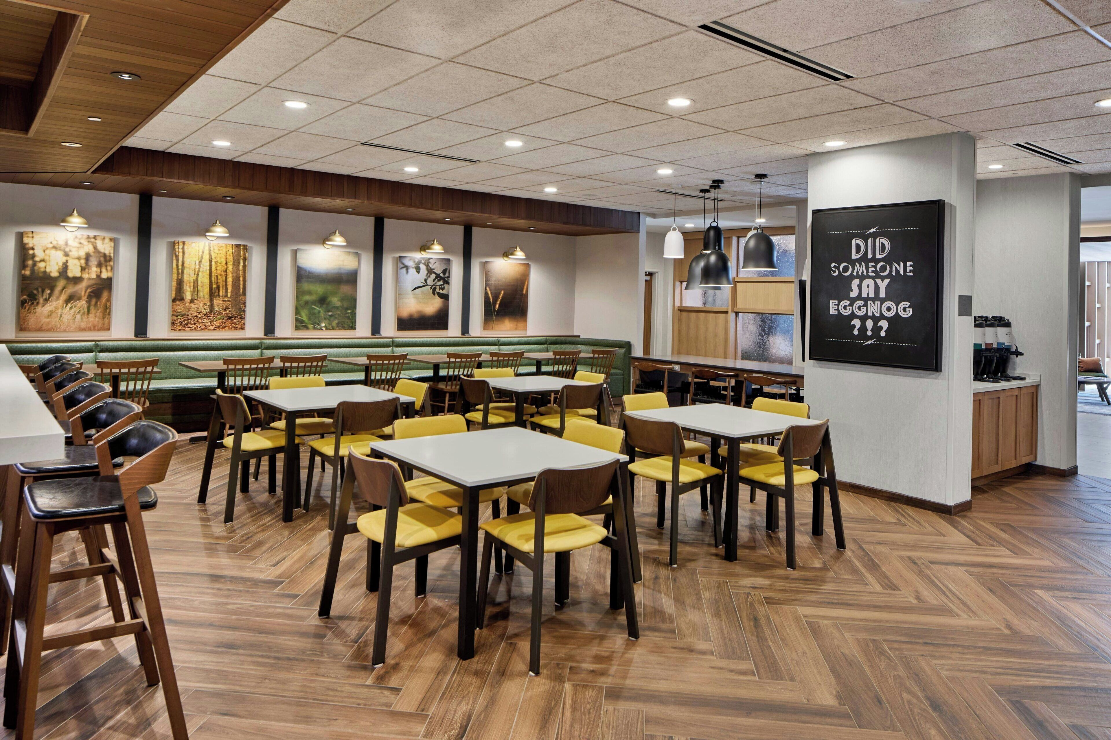 Un restaurant avec des banquettes et des tables, un plancher en bois et des œuvres d’art accrochées aux murs.