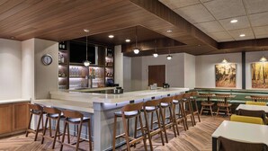 A bar area with wooden bar stools, a counter, and a clock on the wall. - Fairfield By Marriott Inn & Suites Cornelia (Cornelia)
