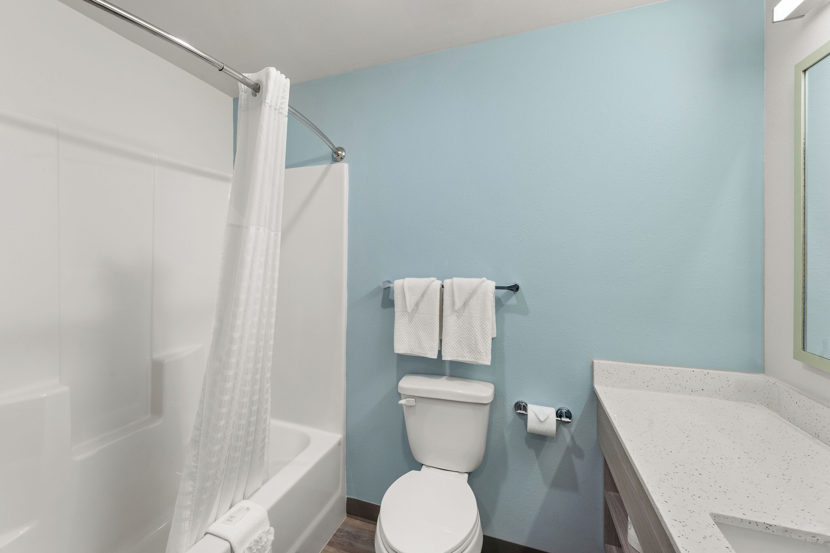 Een badkamer met een witte badkuip, een wit toilet en een witte wastafel met een gevlekt aanrecht.