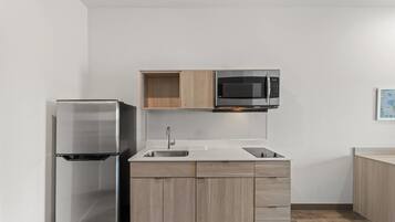 A modern kitchen with a stainless steel refrigerator, a microwave, and wooden cabinets.