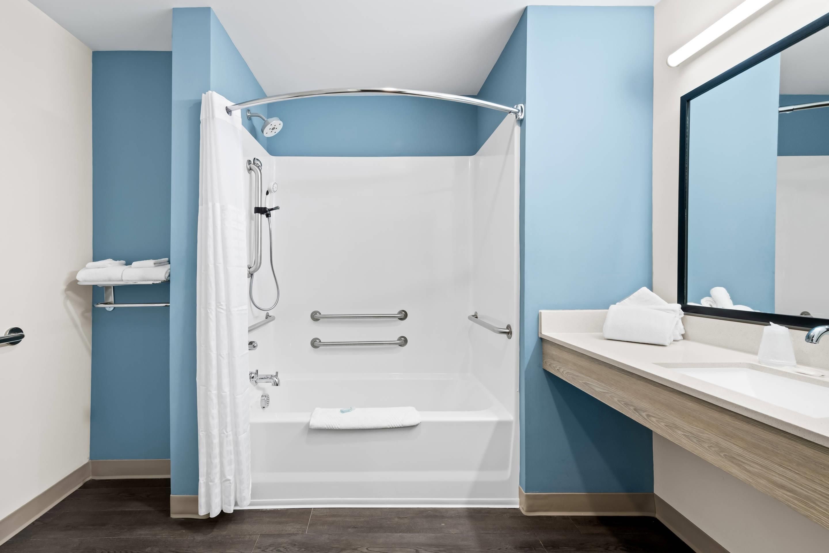 A modern bathroom with a walk-in shower, a vanity with a mirror, and a towel rack.