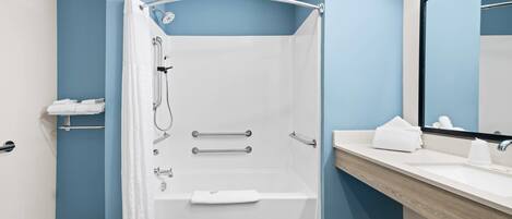 A modern bathroom with a walk-in shower, a vanity with a mirror, and a towel rack.