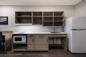 Een moderne keuken met een inbouw magnetron, een spoelbak en een witte koelkast.