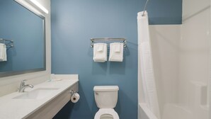 A bathroom with a white sink, a toilet, and a shower curtain. - Woodspring Suites Charlotte Airport (Charlotte)