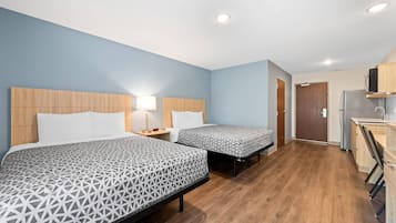 A hotel room with two beds, a kitchenette, and a bathroom.