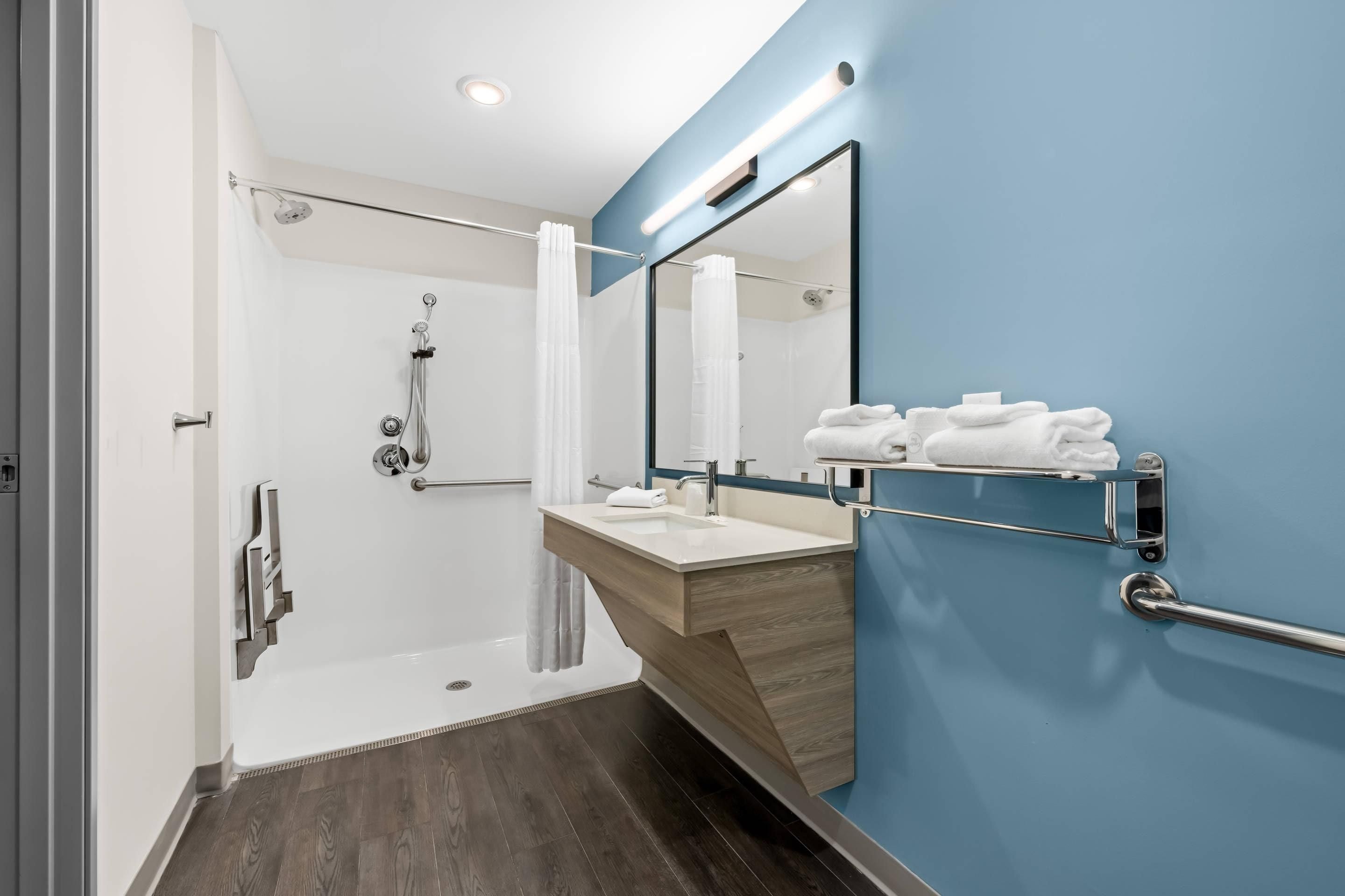 Une salle de bain moderne avec une douche, un lavabo et un miroir.