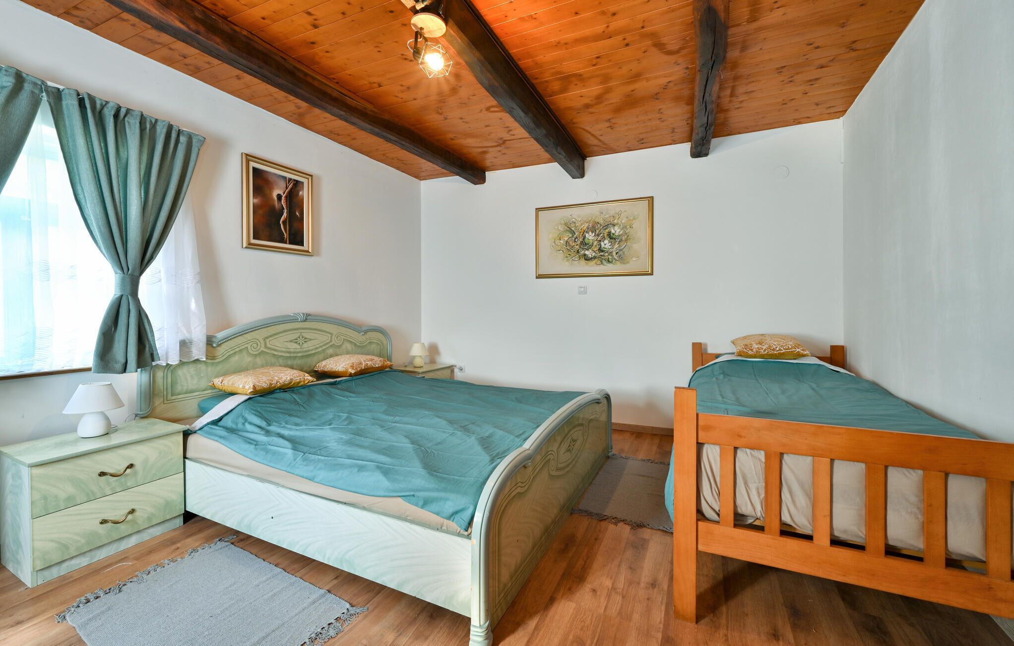 Een slaapkamer met twee bedden, een nachtkastje, een lamp en kunst aan de muren.