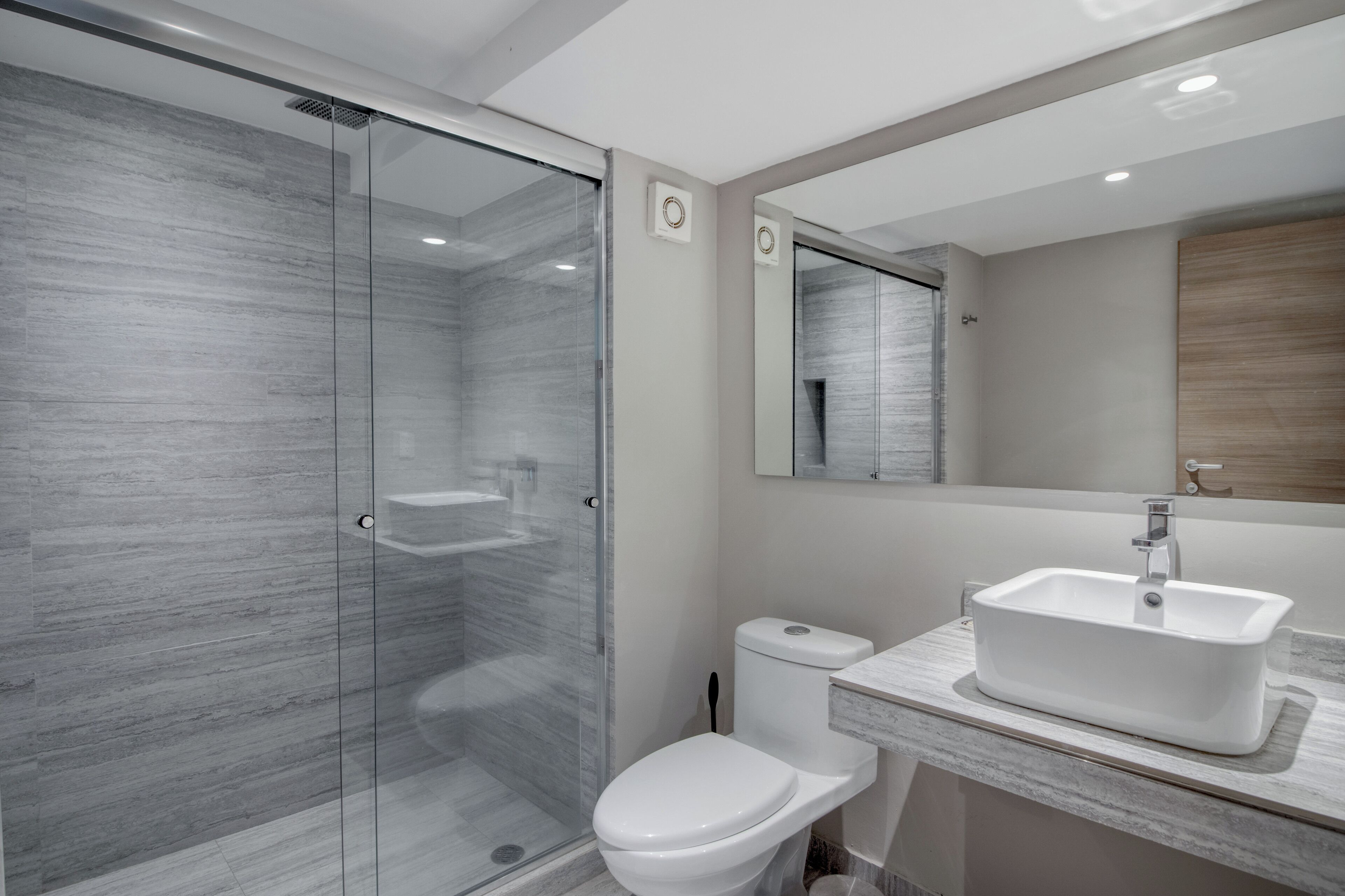 Un bagno moderno con cabina doccia in vetro, un water bianco e un lavabo con piano in marmo.