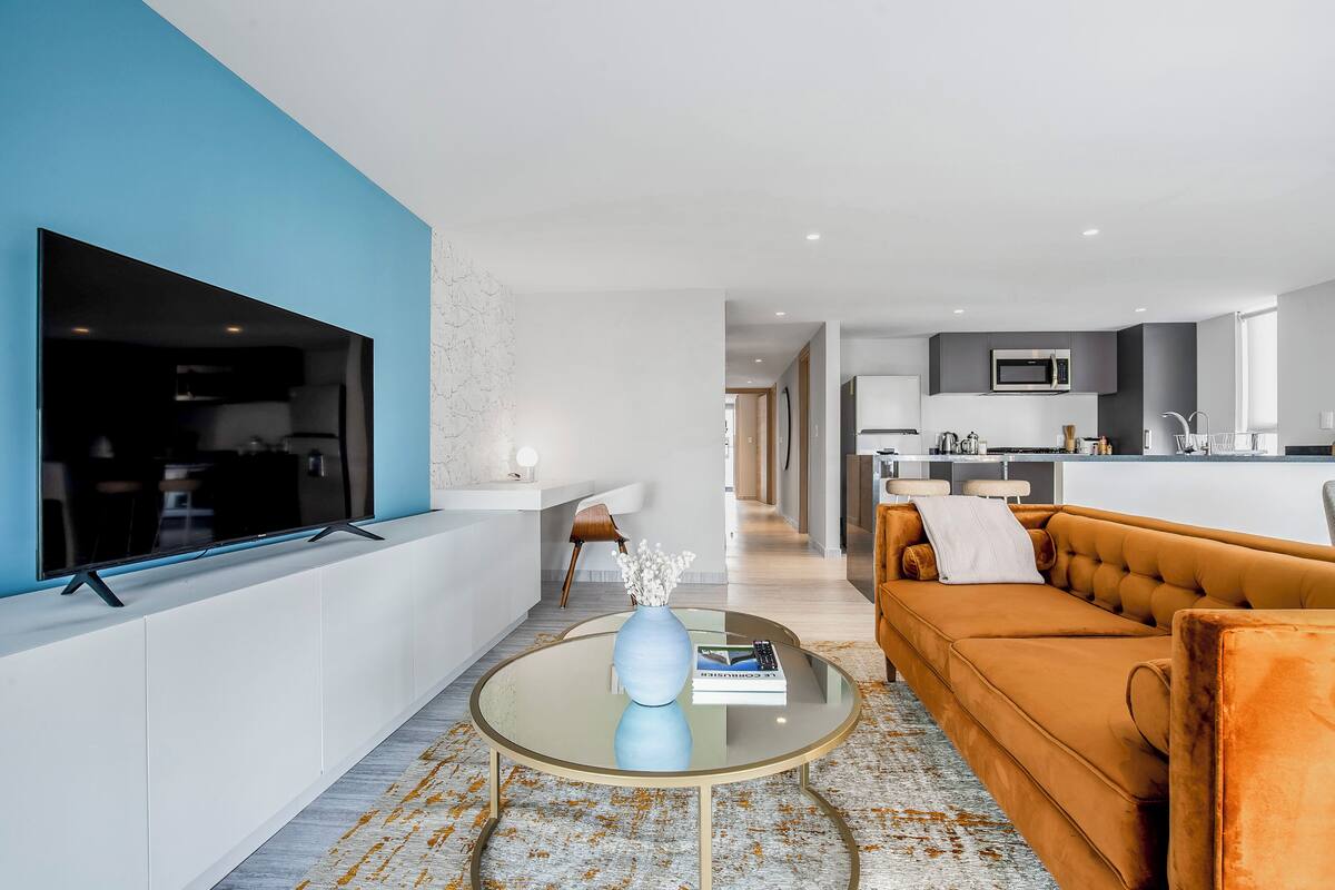 Ein modernes Wohnzimmer mit einer Couch, einem Couchtisch und einem Flachbildfernseher.