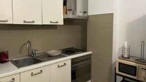 A compact kitchen with a sink, stove, oven, and microwave.