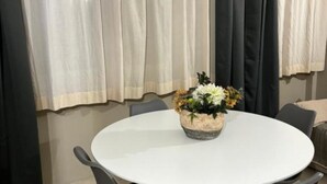 A round white table with a floral centerpiece, surrounded by chairs, in a room with beige curtains and a neutral color scheme.