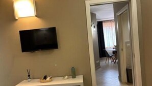 A room with a TV mounted on the wall, a small table with a tray, and a doorway leading to another room.