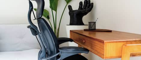 A black office chair with a high backrest and armrests, positioned next to a wooden desk with a drawer.