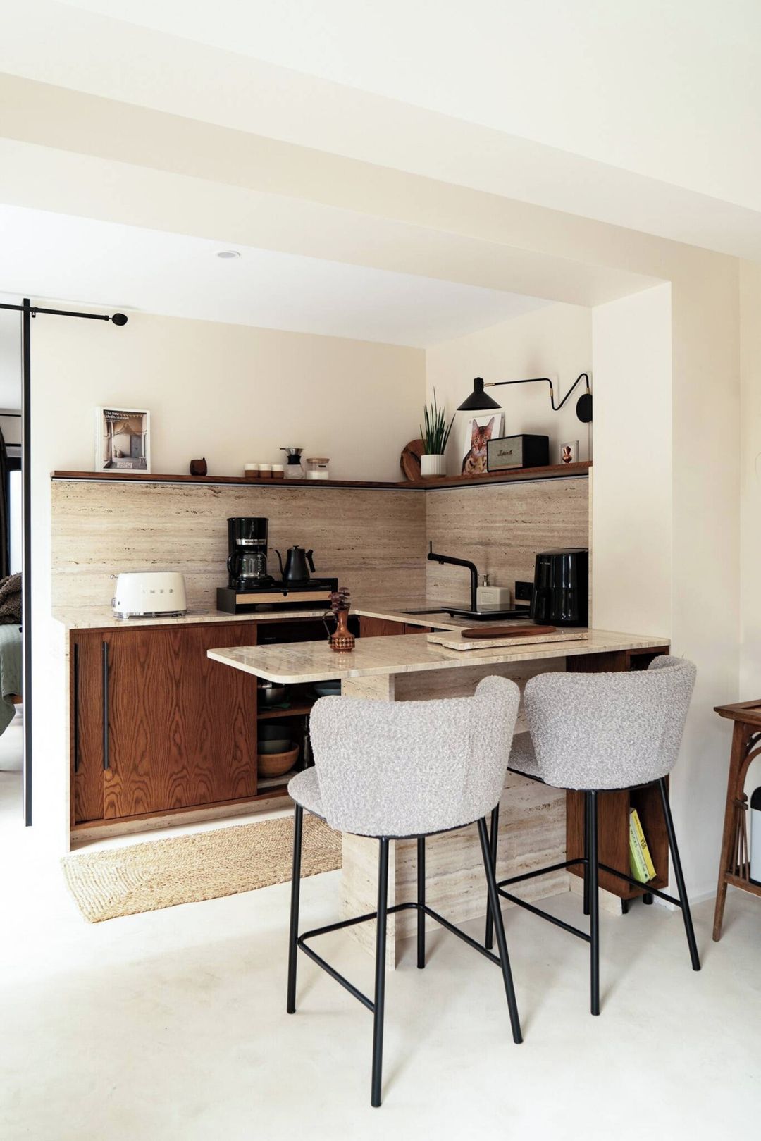 A modern kitchen with a central island, bar stools, and a coffee machine.