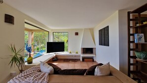 A modern living room with a sofa, a flat-screen TV, a fireplace, and a bookshelf.