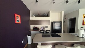 A modern kitchen with a central island, bar stools, a microwave, and a refrigerator.