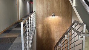 A modern interior with a staircase, a wooden door, and a metal railing.