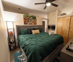 A bedroom with a bed, a ceiling fan, a painting, a wardrobe, and a nightstand. - Private Charming Midtown 1-bedroom apartment in amazing Detroit with WiFi, AC (Detroit)