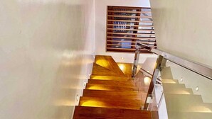 A modern staircase with wooden steps and glass railings. - Charming 2-BR House in San Jose Del Monte w/ WiFi, 3 split-type ACs, & Netflix (San Jose Del Monte)