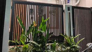 A two-story building with a modern design, featuring a balcony on the upper floor and a gated entrance with vertical slats. - Charming 2-BR House in San Jose Del Monte w/ WiFi, 3 split-type ACs, & Netflix (San Jose Del Monte)