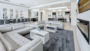 A modern living room with a sectional sofa, a coffee table, and a dining area with chairs and a table. - Really Fun House with tons of room, huge pool plenty to do and a terrific view  (Kissimmee)