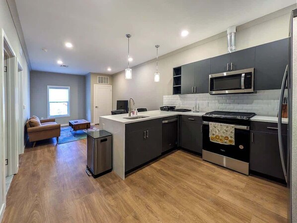 A modern kitchen with dark cabinets, a stainless steel stove, and a microwave.